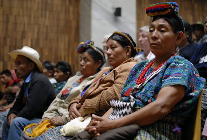 Community members in traditional dress seated together at a gathering